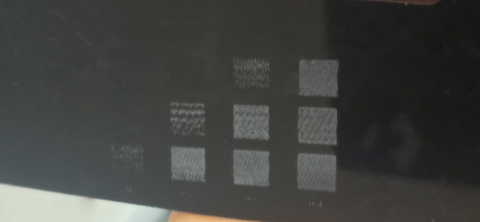 Metacrilato negro con la matriz grabada: las casillas de pocos PPI salen a rayas y las de más PPI en gris uniforme