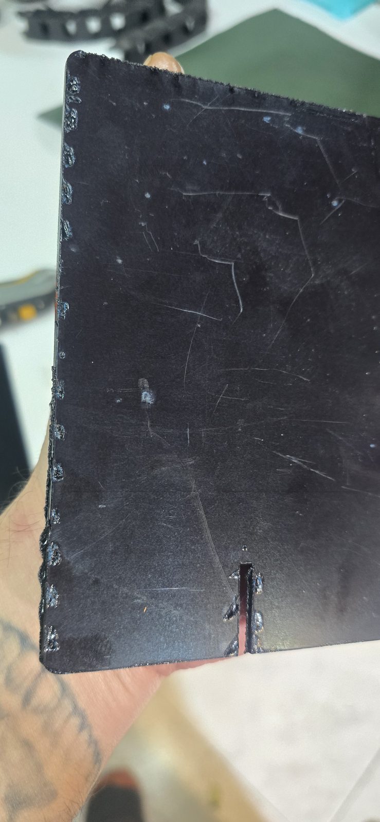 Cara trasera de la pieza de metacrilato negro con puntos marcados a intervalos junto al borde