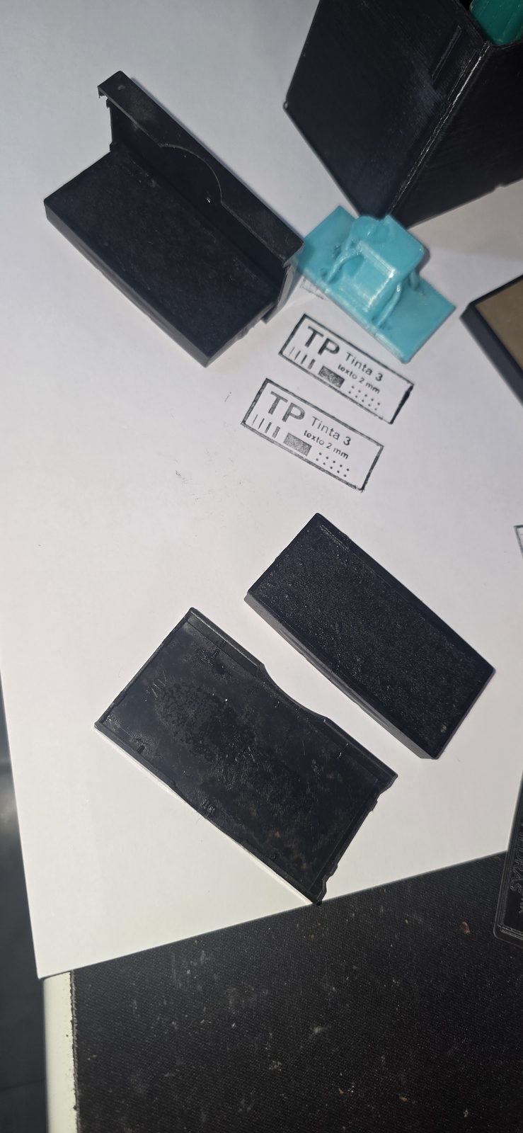 Almohadillas de cartucho negras para re-entintar junto a dos estampados de la plaquita de prueba