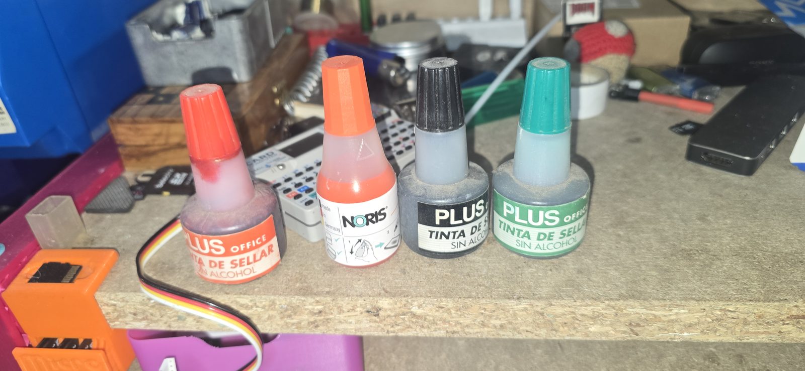 Cuatro botes de tinta de sellar: Plus Office roja, Noris roja, Plus negra y Plus verde
