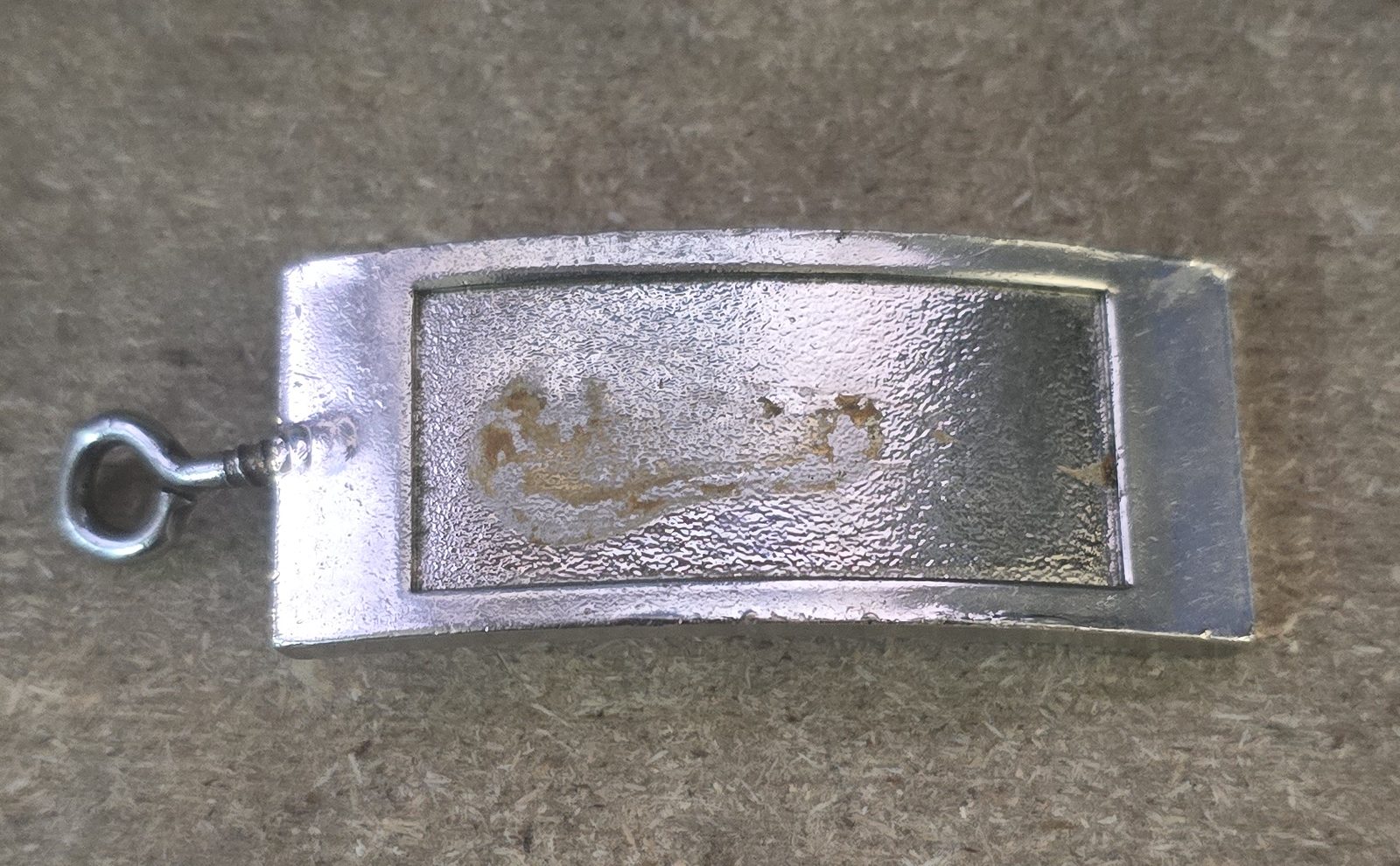 Llavero de metal curvo con un hueco rectangular rebajado en el frente, donde iría la placa