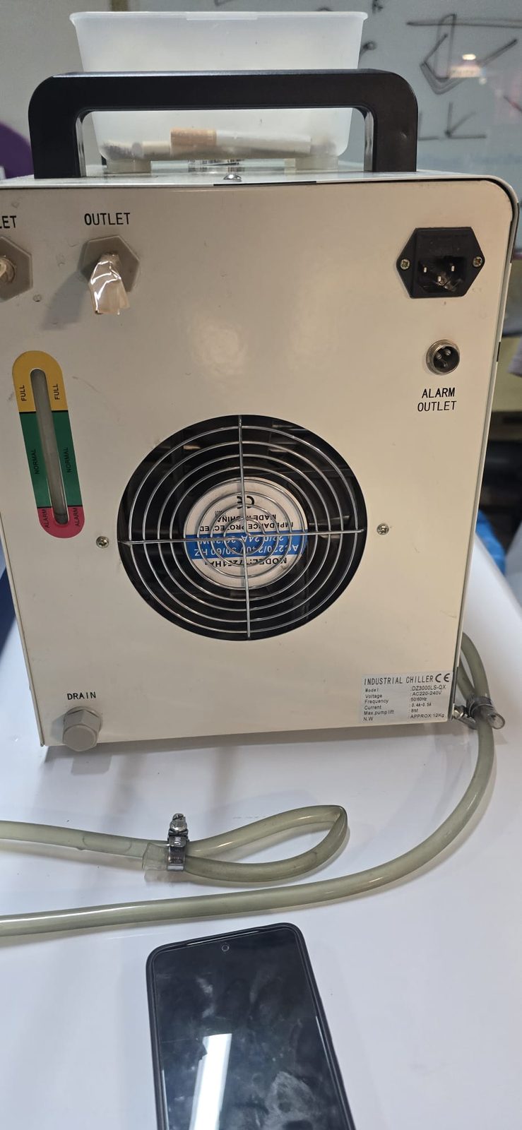 Trasera del chiller: indicador de nivel de agua con zonas FULL, NORMAL y ALARM, ventilador, salida de agua y conector ALARM OUTLET