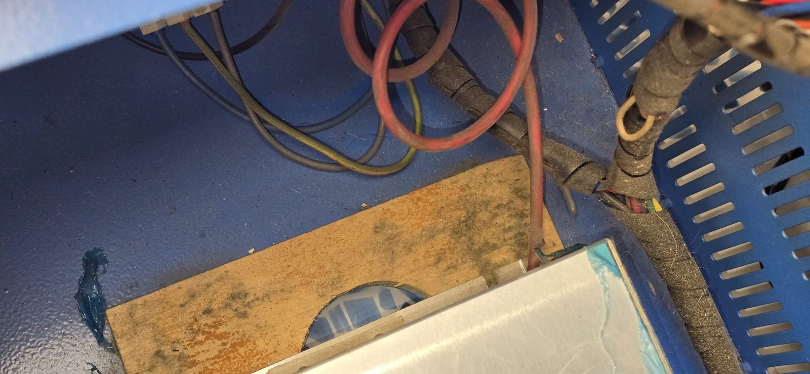 Fuente de alta tensión montada sobre una tabla de madera dentro del compartimento, con cables y el ventilador